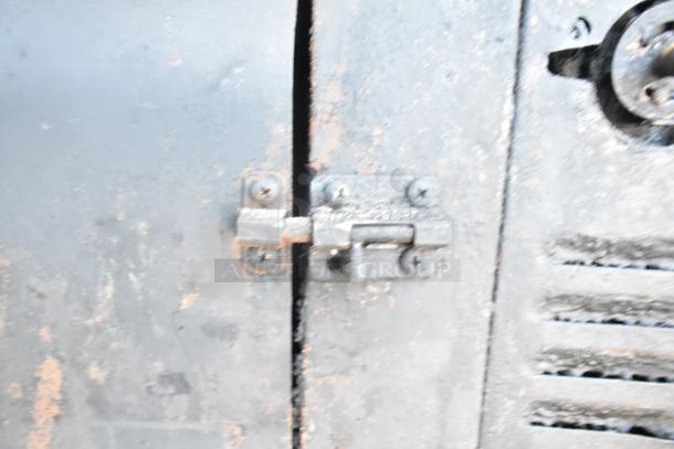 Close-up of Blodgett 981 commercial pizza oven latch. Metal surface shows wear. Natural gas-powered, 50,000 BTU, 2 decks.