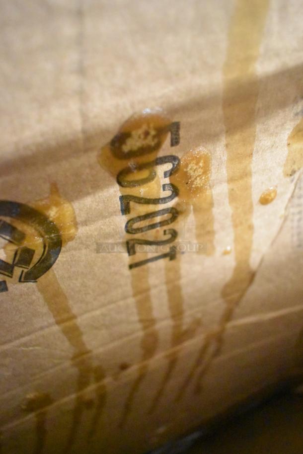 Cardboard box detail with smudged label and liquid streaks; condition unclear. Image relates to an auction lot of new scratch and dent items.