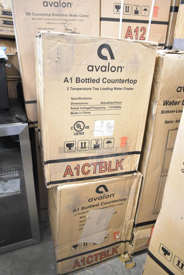 Cardboard boxes of Avalon A1CTBLK Premium Hot/Cold Top Loading Countertop Water Coolers, new, with product specs visible.