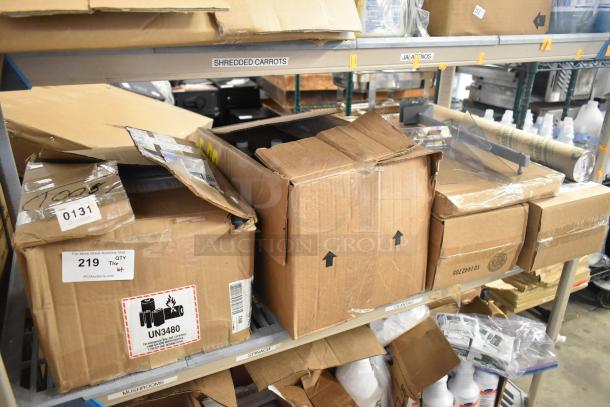 Tiered lot of various items including unopened Diversey Emulsion ProX. Boxes in warehouse, some labels showing UN3480 and quantity.