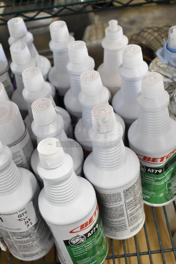 Two-tier lot of cleaning supplies featuring Betco AF79 cleaner, visible labels, on metal shelf.