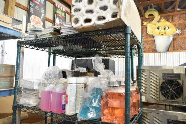 Two-tier wire shelf with 1099 envelopes, hand sanitizer bottles, Scott foam cleanser, and Claire disinfectant spray.