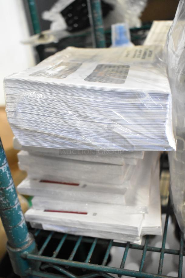 Two-tier lot with 1099 envelopes, hand sanitizer, Scott Foam Skin Cleanser, Claire Disinfectant Spray, on metal rack.