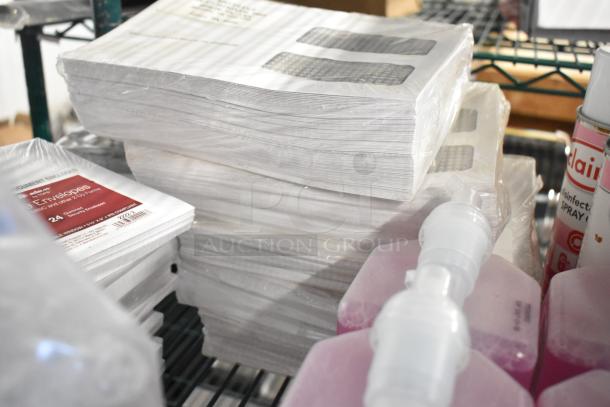 Two-tier lot of assorted items featuring 1099 envelopes, hand sanitizer, Scott foam cleanser, and Claire disinfectant spray.