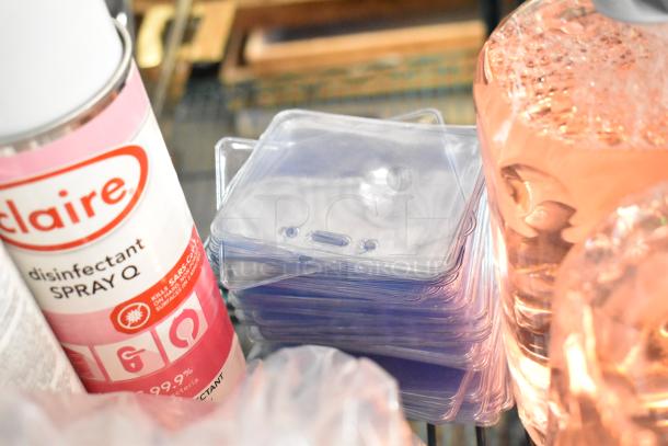 Two-tier lot including Claire disinfectant spray, clear plastic items stacked, and partially visible bottled liquids.