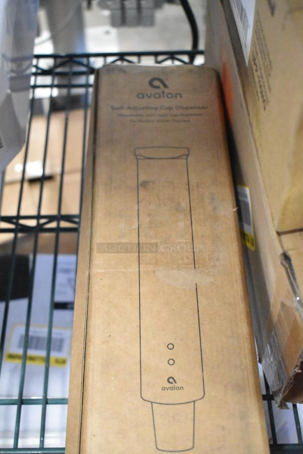 Boxed Avalon self-adjusting cup dispenser, new condition, labeled with Avalon logo and dispenser outline.