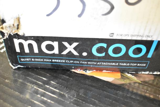 Damaged box for Max Breeze 6-inch clip-on fan; features attachable table-top base.