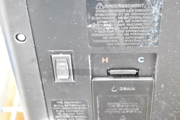 Close-up of Keurig K-2550 coffee machine showing power switch, hot and cold settings, and warning labels.