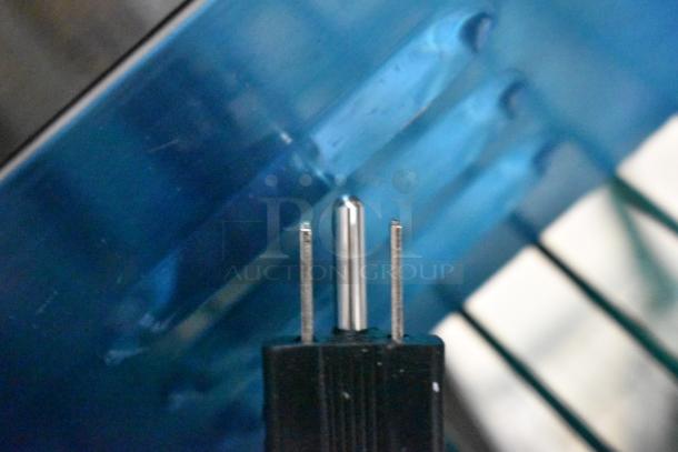 Electrical plug of Avantco 177PG400 Panini Grill against a blue background, showing three metal prongs.