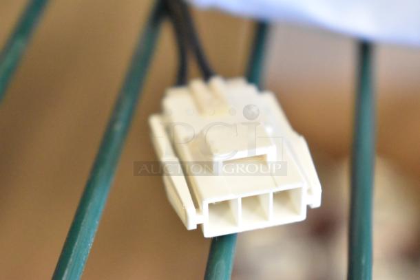 White plastic electrical connector on green metal bars, part of Avantco refrigeration motor components.