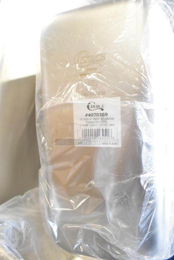 12 new scratch and dent items, including Choice stainless steel bins and stock pot, wrapped in plastic with visible labels.