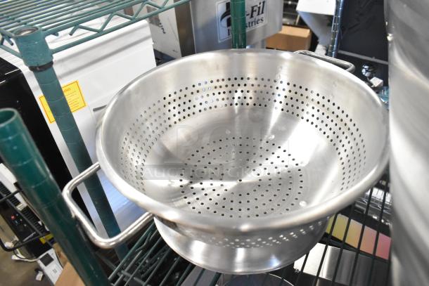 Stainless steel colander on a shelf; part of 12 brand new scratch and dent kitchen items, including drop-in bins and stock pot.