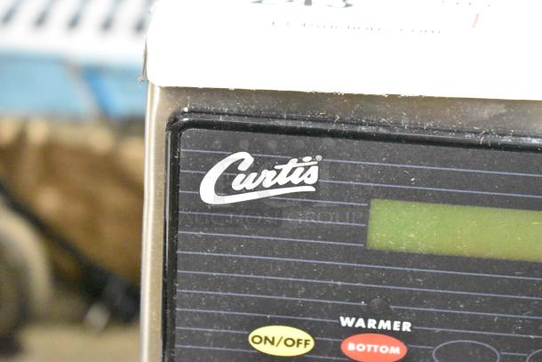 BRAND NEW SCRATCH AND DENT Curtis ALP1GT12A000 12 Cup Coffee Brewer with display and control buttons visible.