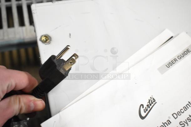 BRAND NEW Curtis ALP1GT12A000 coffee brewer, 12-cup, with lower warmer. Shows plug and user guide. 120 Volts. Scratch and dent condition.