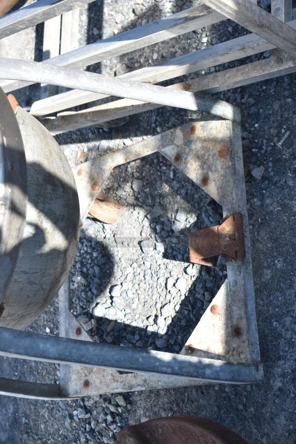 Metal mixing bowl on dolly, shown in outdoor lighting. Bowl and dolly appear weathered with visible rust spots.