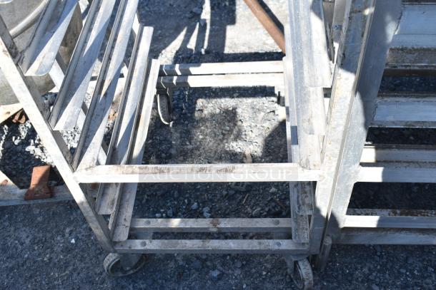 Channel metal commercial pan rack with casters, showing visible wear and rust, designed for heavy-duty kitchen use.