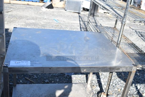 Commercial metal table with an undershelf, used condition, sturdy construction, auction tag visible with item details.