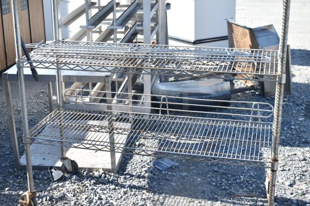 Chrome finish 4-tier wire shelving unit with caster wheels. Shelves show signs of wear. Buyer must dismantle.