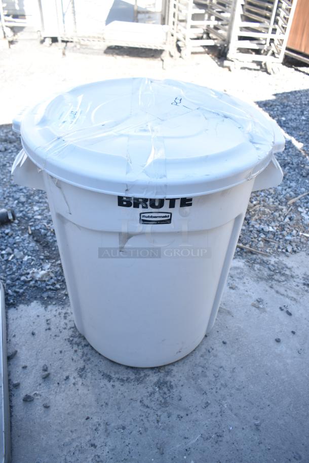Brand new Rubbermaid Brute white poly trash can with lid and dolly, visible scratches and dents.