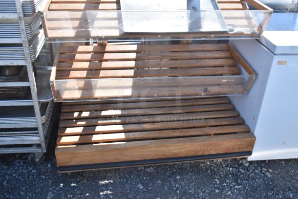 Wooden produce merchandising shelf with three slatted tiers, clear acrylic fronts, and sturdy construction. Good condition.