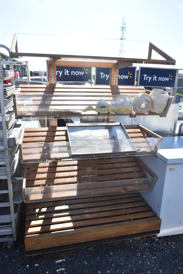 Wooden produce merchandising shelf with slatted tiers, clear front panels, and an attached label. Used condition.