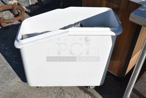 White poly ingredient bin on commercial casters, containing round cake pans, in used condition.