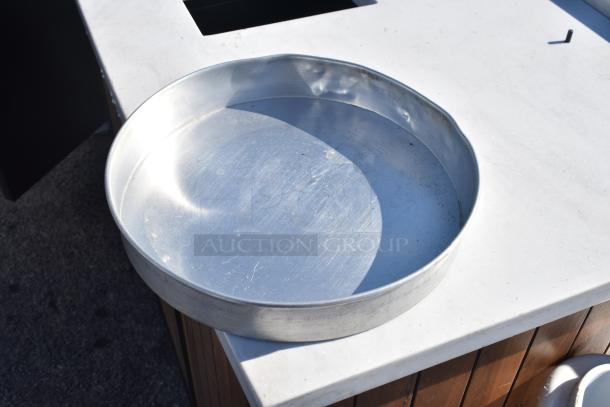 Round aluminum cake pan on a white surface, showing light wear and scratches. Suitable for baking or storage use.