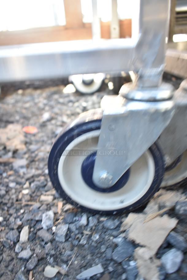 Blurry close-up of a caster wheel on a Winholt commercial pan rack.