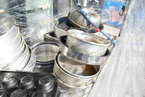 Chrome finish 4-tier wire shelving unit on commercial casters holding metal trays. Buyer must dismantle.