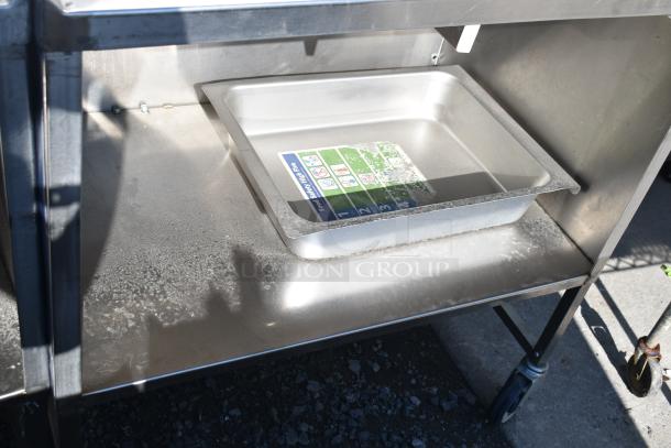 Commercial portable counter with under shelf, drawer, and commercial casters. Metal construction, used condition.