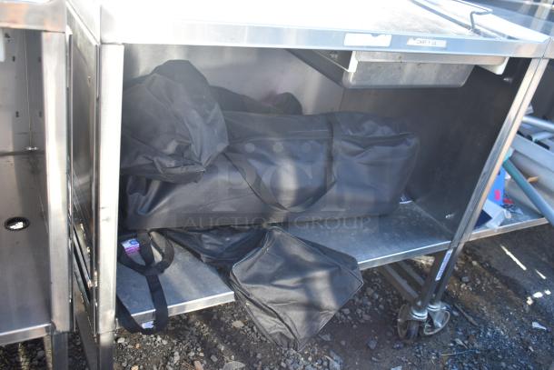 National Cart portable counter with under shelf and drawer, on commercial casters; includes storage bags underneath.