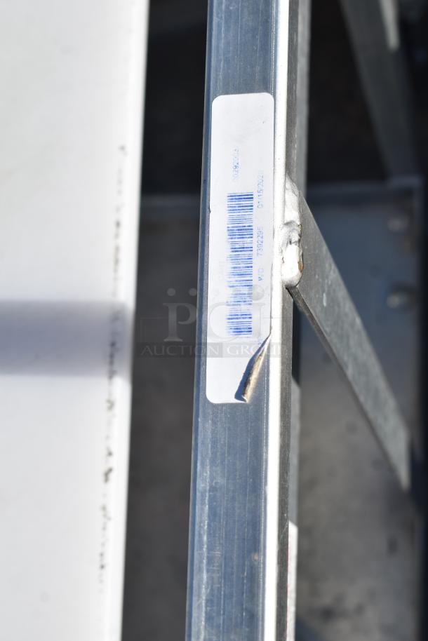 Commercial Pan Rack in good condition with metal frame, sturdy construction, on commercial casters. Visible barcode label.