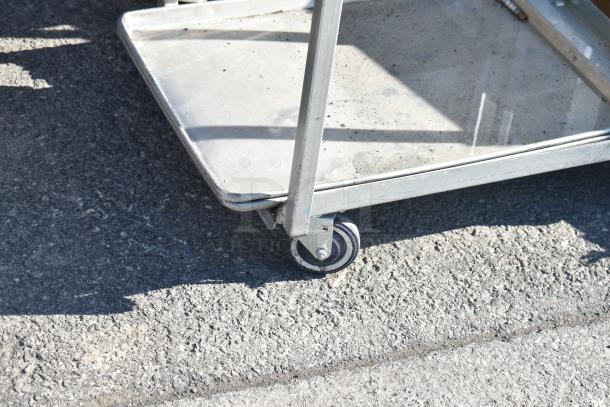 Commercial pan rack on casters, metal frame with multiple shelves, used condition, sturdy wheels for easy mobility.