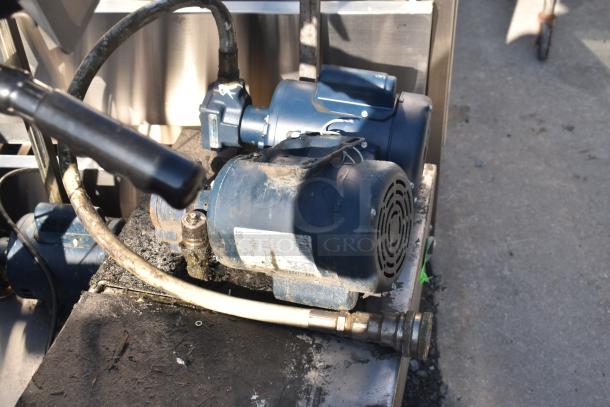 A worn blue motor with attached hoses and visible dirt, possibly used in industrial settings, displayed on a metal surface.