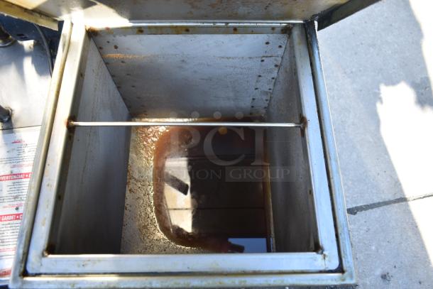 Steel container with scratches, rust stains, and residual liquid inside. Auction item part of a set including wire shelves.