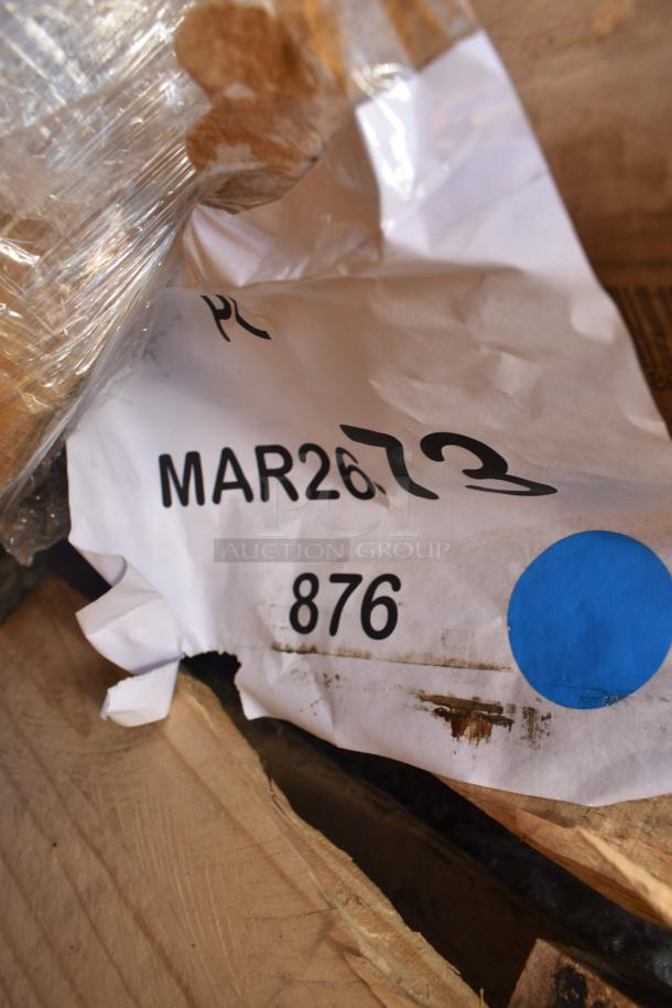 Label showing lot number MAR26-73 and number 876 on packaging of scratch and dent auction items, including shelves and pan racks.