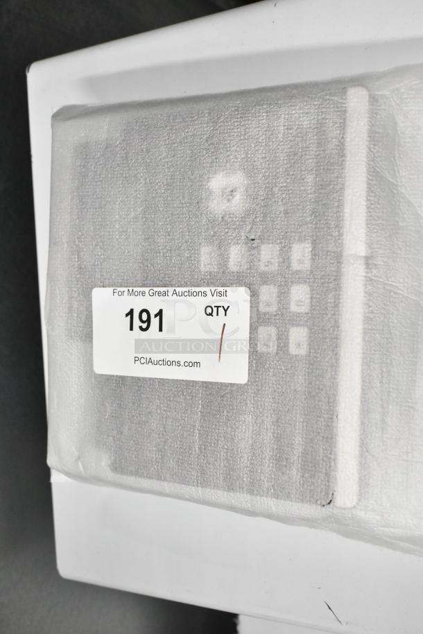 Corded office telephone wrapped in packaging, label reads "For More Great Auctions Visit PCIauctions.com, 191 QTY 1."