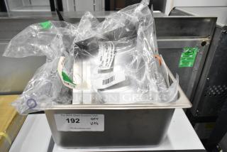 Six brand new scratch and dent items, including a condenser drain pan, door handle, bracket, and brush hanger, labeled with auction tag 192.