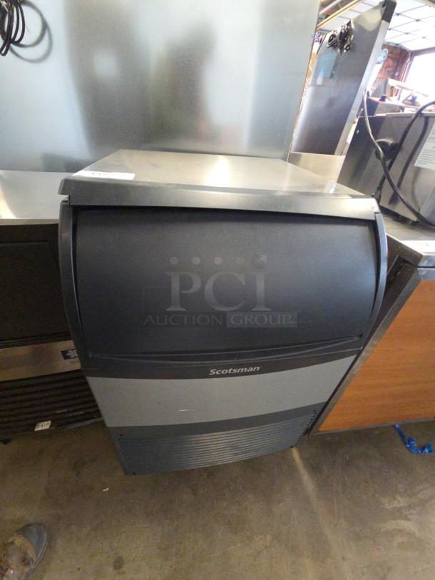 Scotsman undercounter ice maker, black and gray finish, stainless steel top, visible "Scotsman" label, commercial use.