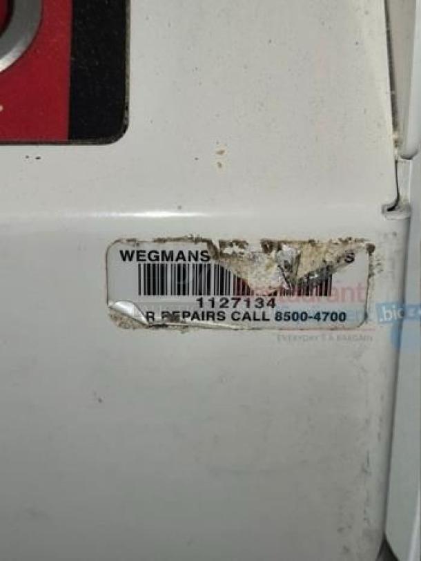 JAC VPL770 Varia Pro bread loaf slicer with visible Wegmans service tag and contact number; white surface with slight wear.