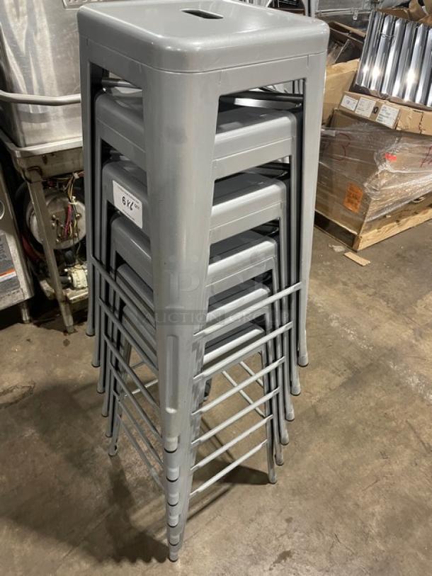 Like new Astor welded bar height silver dining chairs, stack of six. Durable metal, sleek finish, model number tag visible.