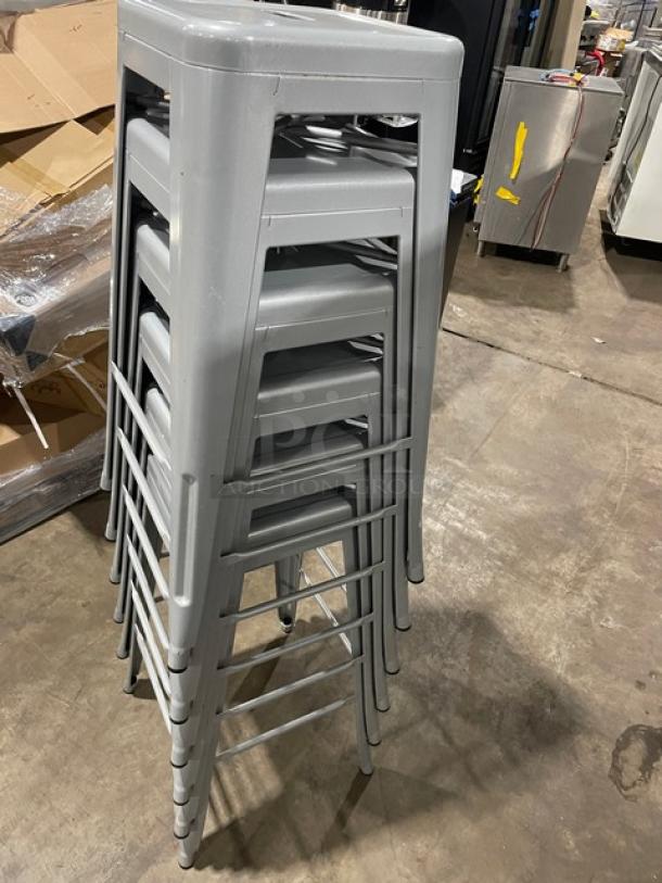 Stack of six like-new Astor welded bar height silver dining chairs, durable metal construction, ideal for stylish seating.