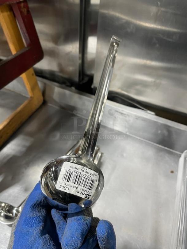 Winco LDI-3 stainless steel 3oz ladle, commercial grade, new with label visible on handle, held by gloved hand.