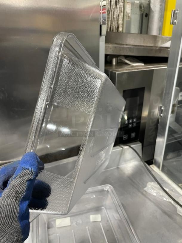 Rubbermaid Model 3307 clear polycarbonate food storage container, 18x12x3.5 inches. New condition, held by gloved hand.