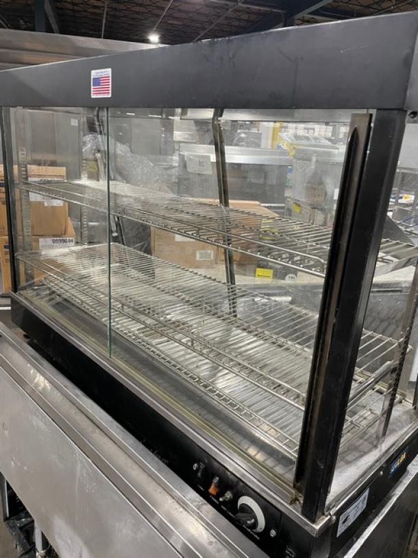 Adcraft 48" heated display showcase, multi-tier flat glass, chrome-plated wired rack, rear sliding doors, 120V, used condition.