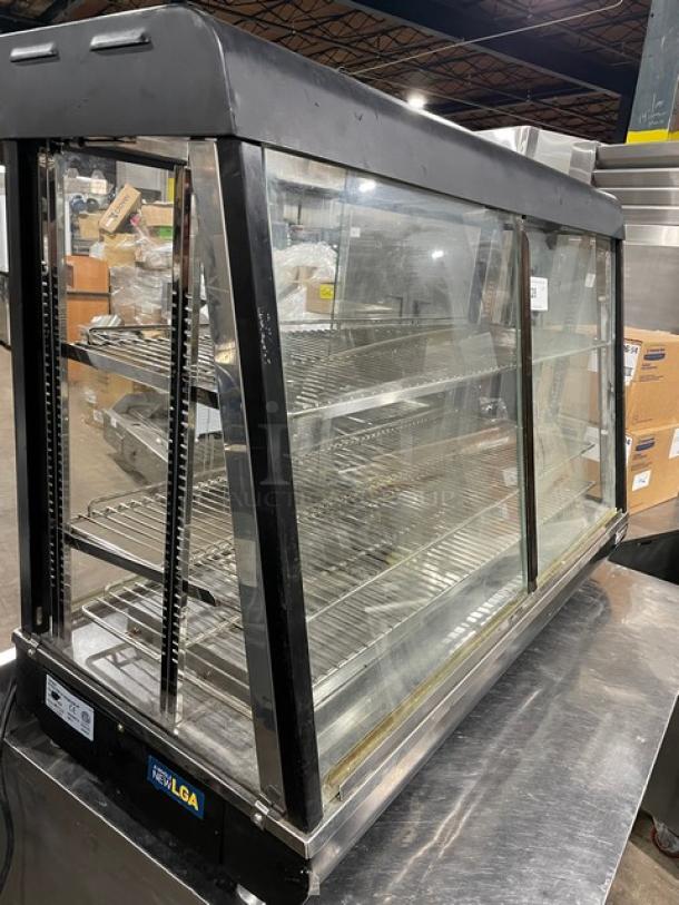 Adcraft 48" heated display showcase with multi-tier chrome rack, flat glass panels, and rear sliding doors, in used condition.
