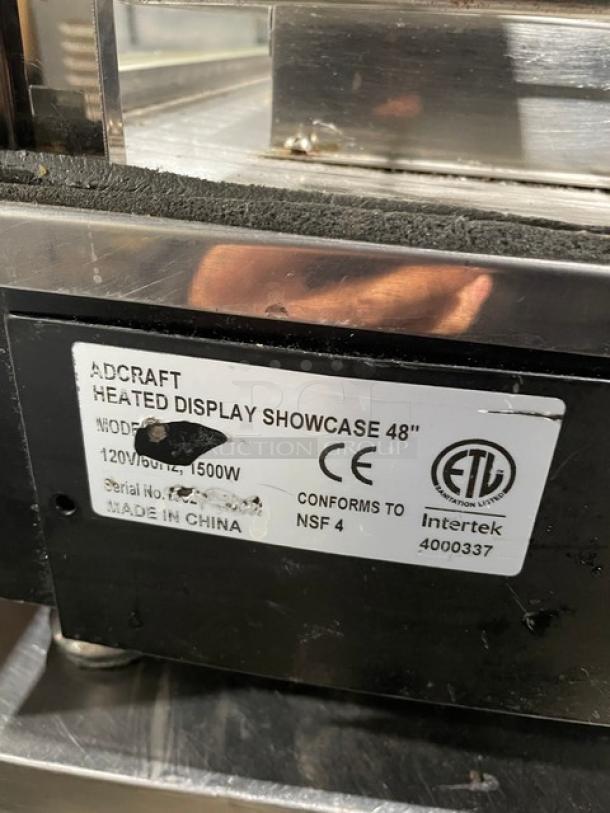 Adcraft 48" Heated Display Showcase, multi-tier, chrome rack, rear sliding doors, model info tag indicating 120V, 1500W.