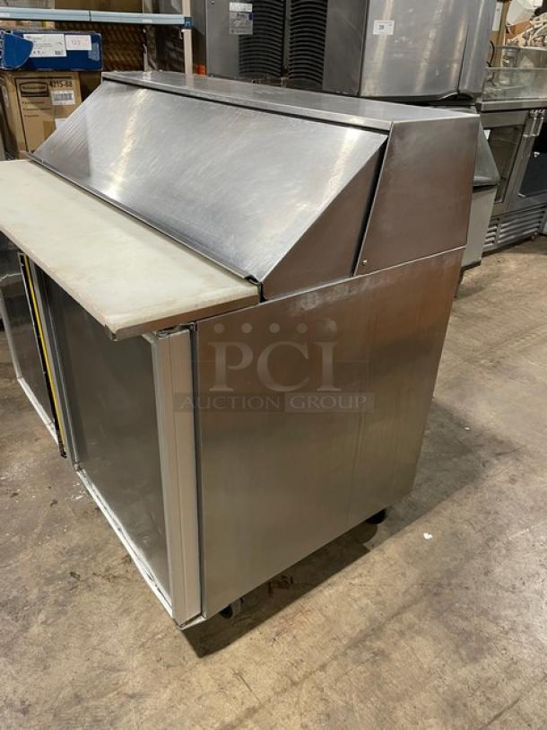 Commercial stainless steel refrigerated prep table with bain marie style, cutting board, and casters. Used condition.
