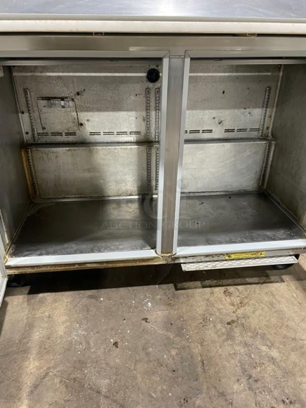Commercial stainless steel refrigerated bain marie prep table with cutting board, on casters, interior view.