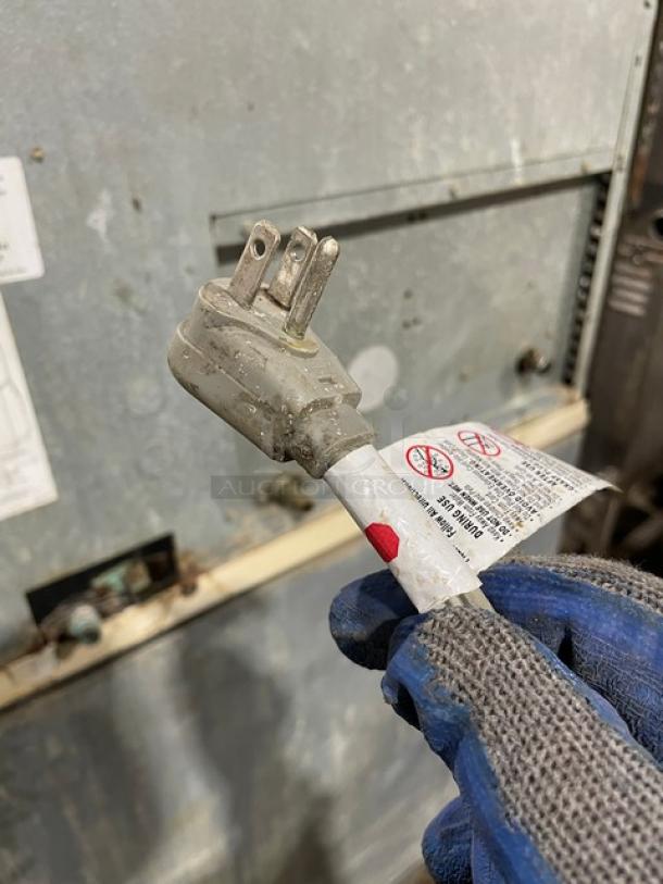 Manitowoc stainless steel electric ice machine combo, lift open access, on legs. Includes visible tags with safety warnings.